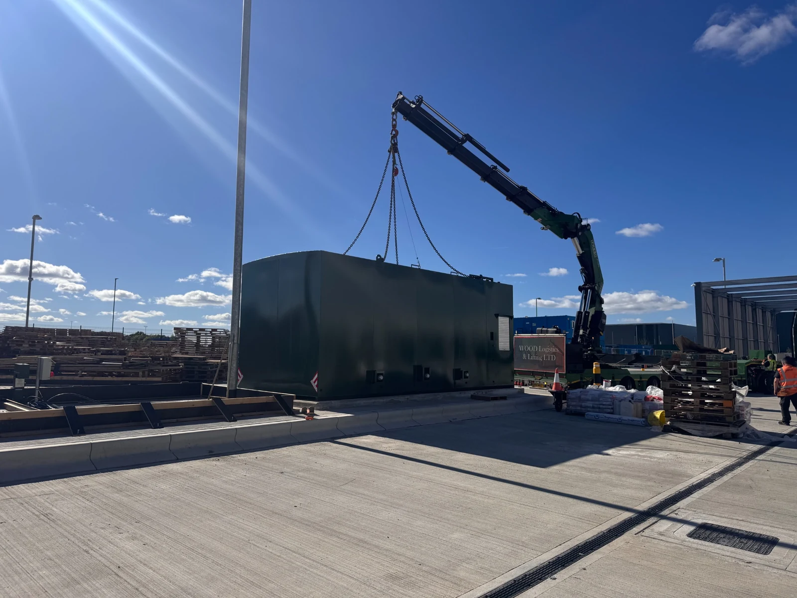 A crane positioning a fuel storage tank at a commercial site.